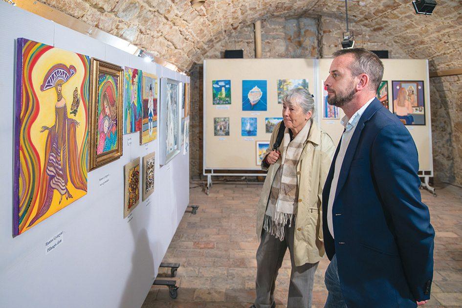 A Kortalanul Kreatív című kiállítás képeit szemléli két látogató.